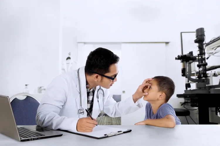 Doctor assessing child's vision during developmental screening in Singapore GP clinic.