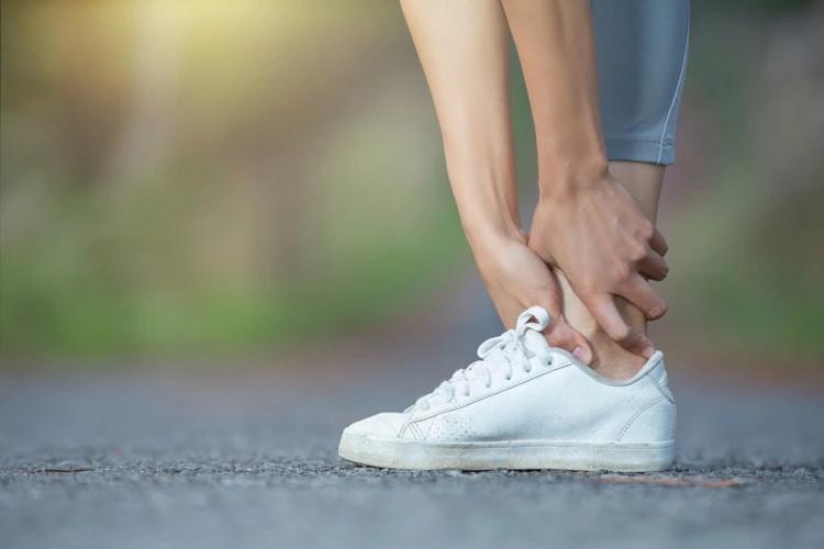 Person stopped walking and grasping her heel due to pain felt inside it.