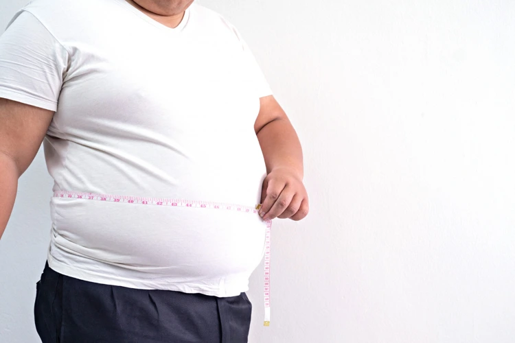 Man with weight issues measuring his waist with a measuring tape.